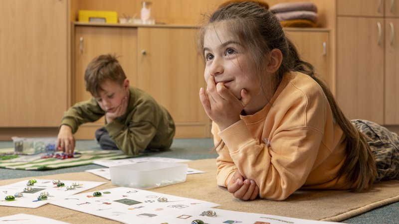 Zwei Kinder lernen mit bunten Steinen.