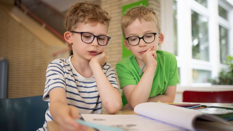 Zwei Grundschüler schauen auf ein Arbeitspapier.