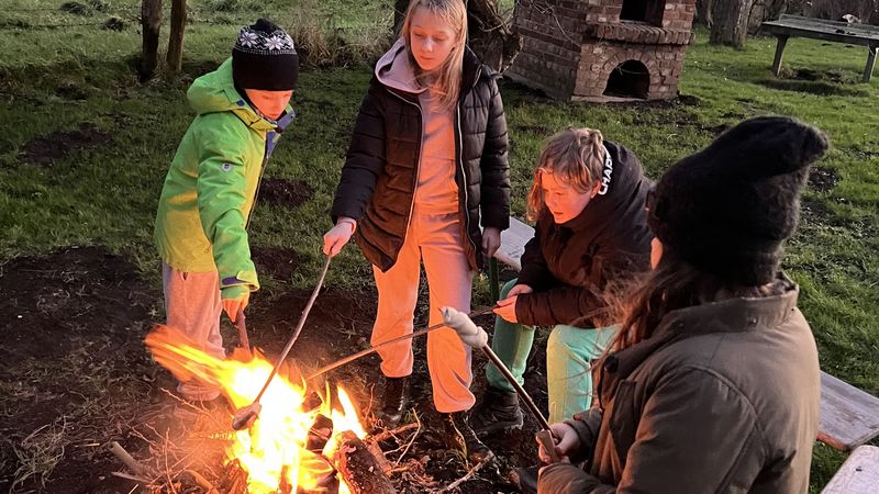 Kinder sitzen am Lagerfeuer.